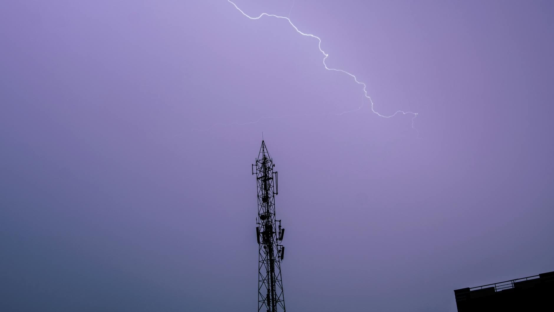 Błyskawica rozświetla nocne niebo nad wieżą telekomunikacyjną